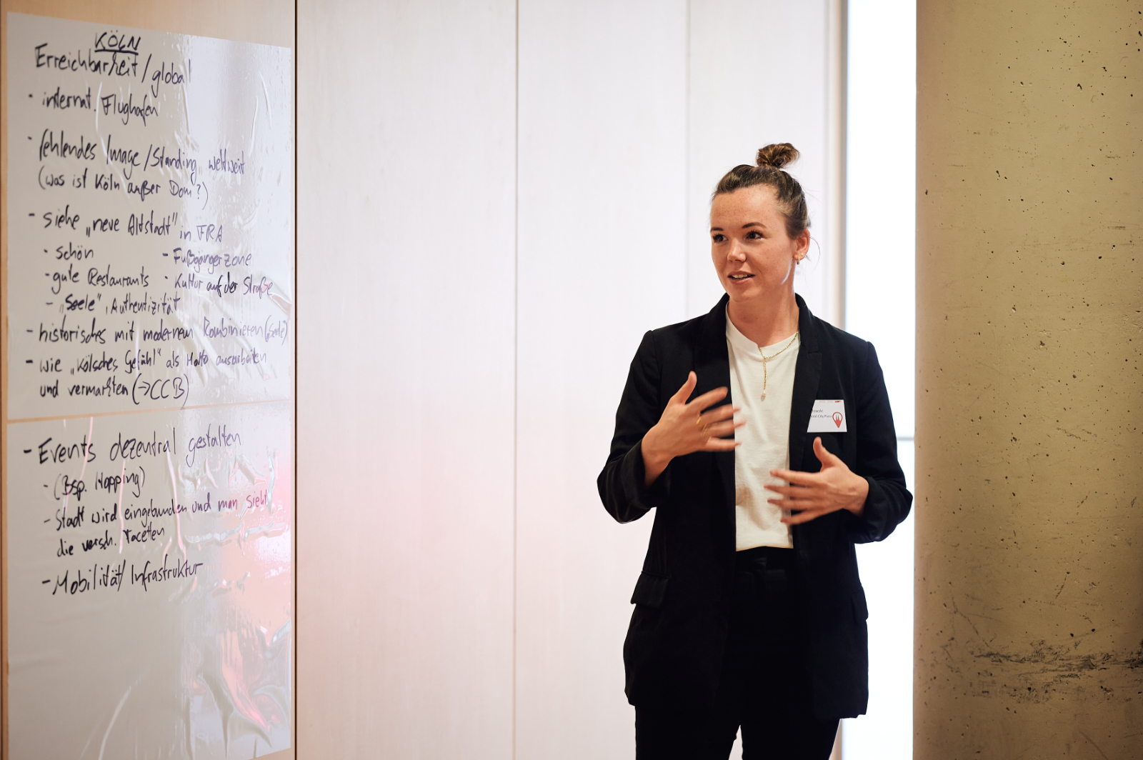 Eine Frau steht neben einem Flipchart und präsentiert gestikulierend