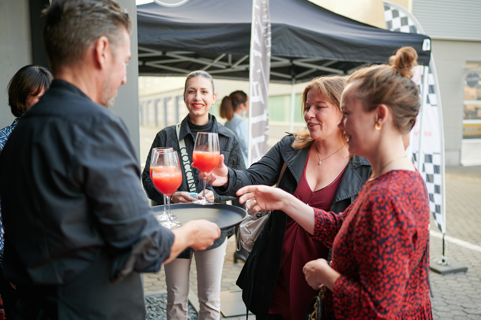 Veranstaltungsgäste nehmen Getränke vom Tablett