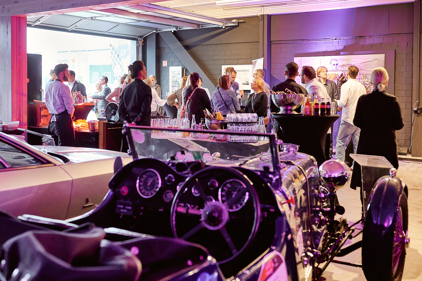 Veranstaltungsgäste unterhalten sich, im Vordergrund steht ein Oldtimer