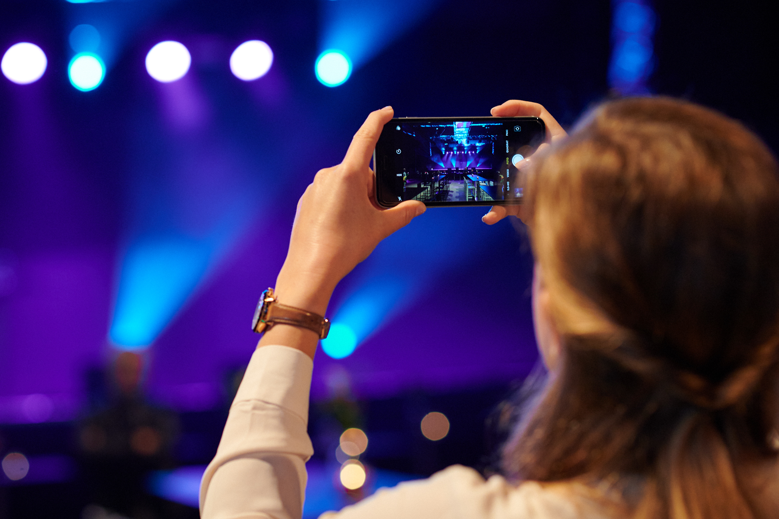 Eine Frau fotografiert die leere Bühne mit ihrem Handy