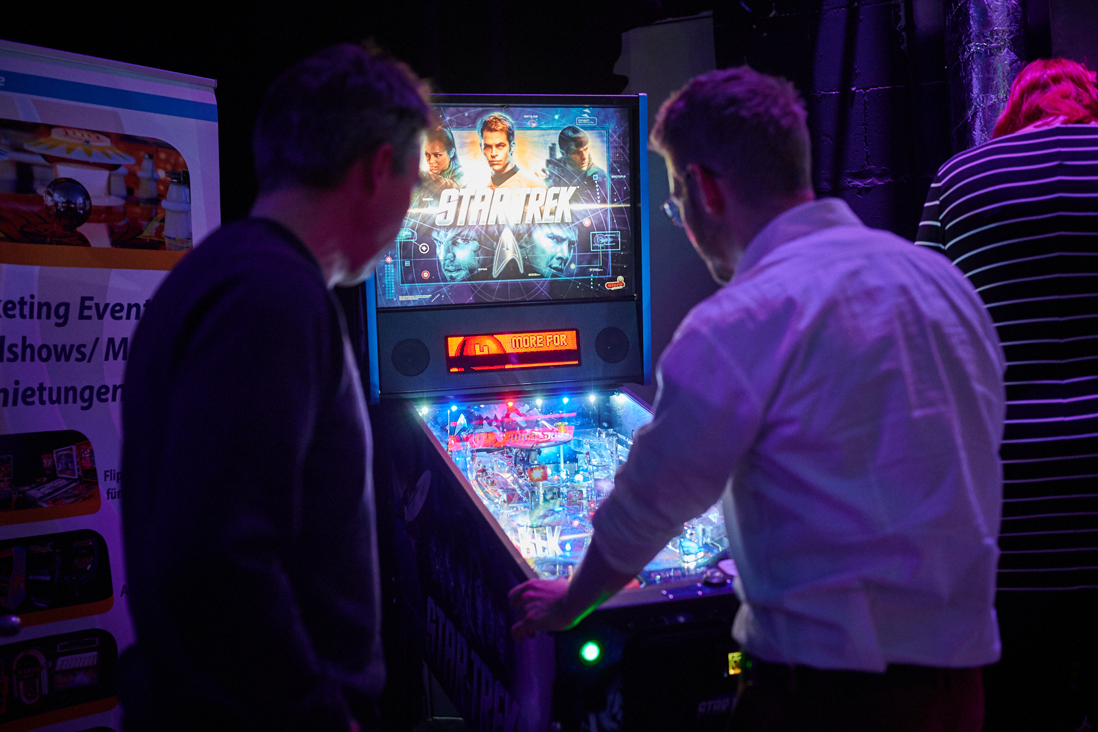 Zwei Personen stehen am Spieleautomaten