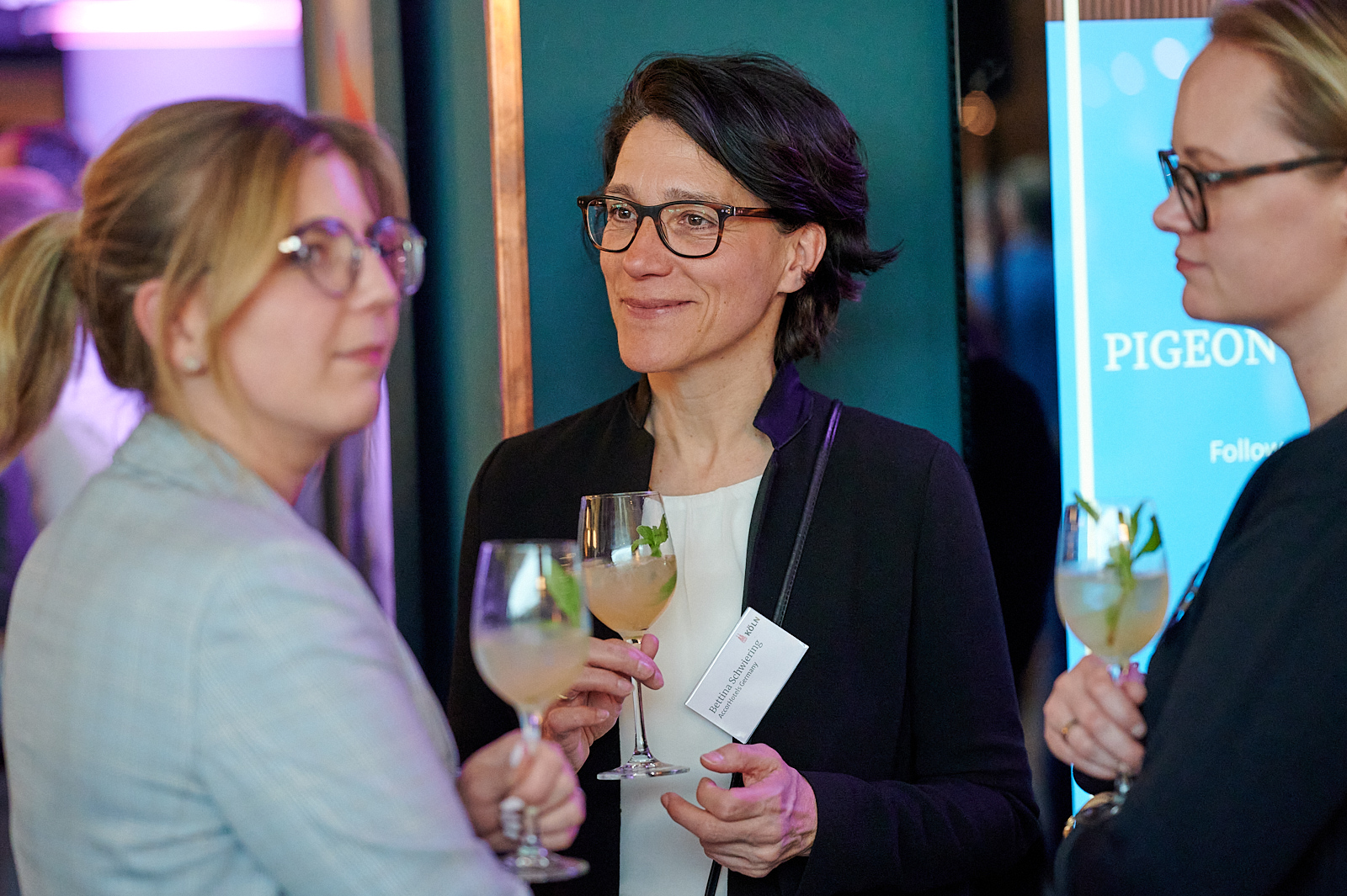 Gäste unterhalten sich beim Networking mit Getränken in den Händen