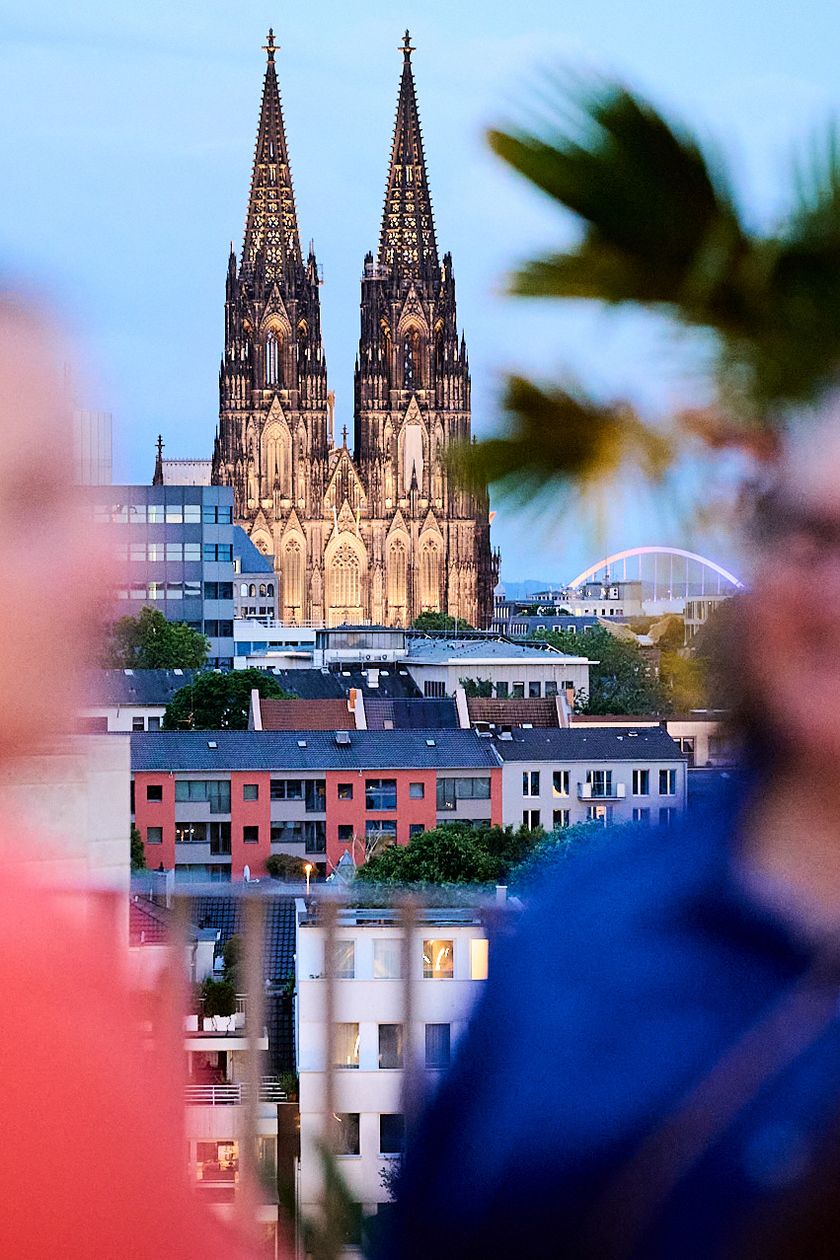 Personen unterhalten sich auf der Terrasse der Monkey Bar, im Hintergrund der Dom