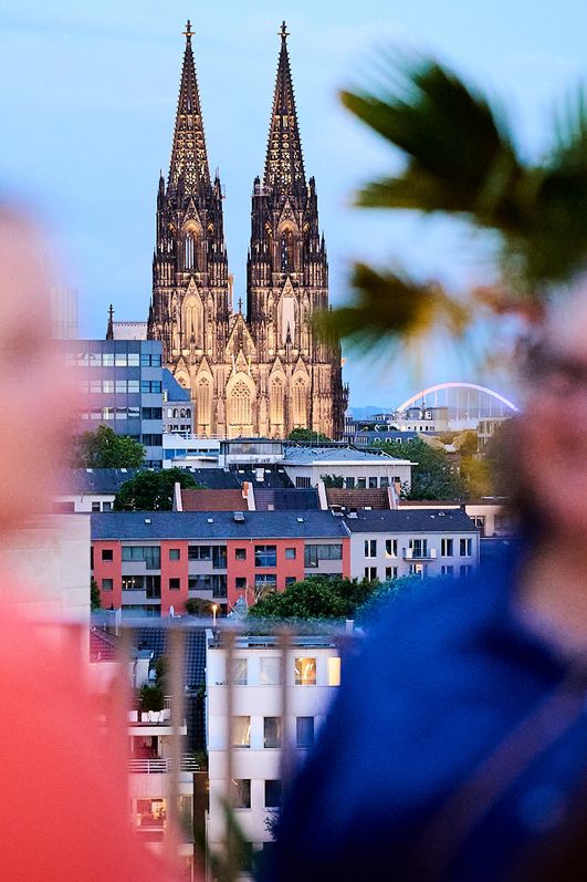 Personen unterhalten sich auf der Terrasse der Monkey Bar, im Hintergrund der Dom