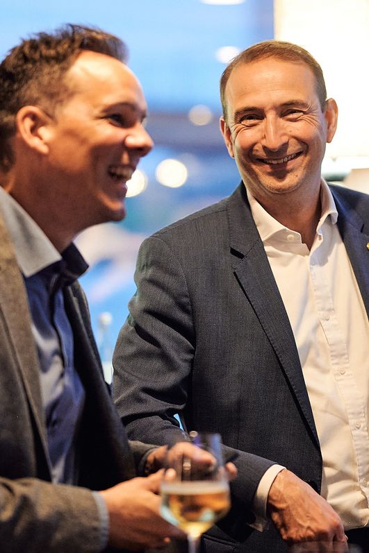 Zwei Männer stehen nebeneinander und lachen