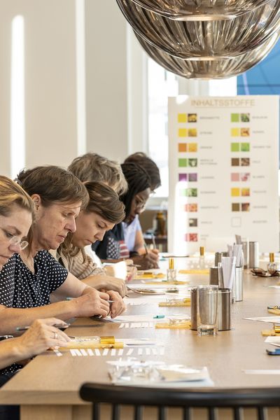 Parfum Workshop: Eine Personengruppe sitzt an einem Tisch und schreibt