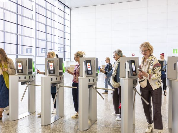 Menschen laufen durch ein Drehkreuz mit digitalem Ticketsystem