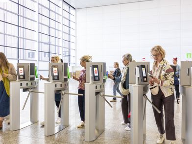 Menschen laufen durch ein Drehkreuz mit digitalem Ticketsystem