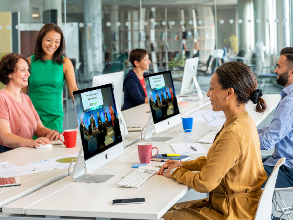 Coworking: 4 Personen sitzen an einem Tisch und arbeiten am PC