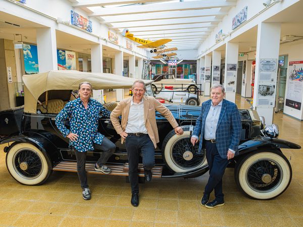Hubert Sterzinger, Andreas Duenkel und Norbert Haug lehnen am Oldtimer in der Motorworld Köln