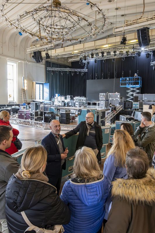 Gruppe besichtigt den Gürzenich Köln, im Hintergrund wird eine Bühne und Technik aufgebaut