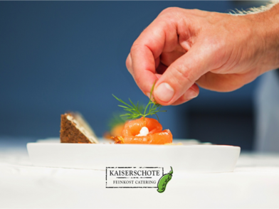Eine Hand garniert eingerollten Lachs mit Dill. Titelbild von Kaiserschote Feinkost Catering.