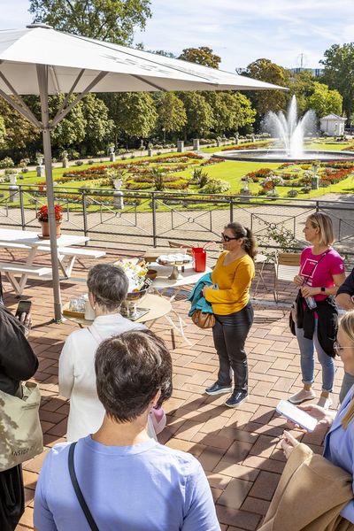 Gruppe steht im Kreis auf einer Terrasse mit Blick in den Botanischen Garten Köln