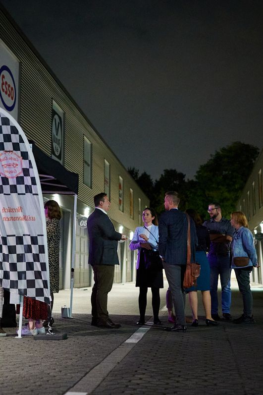 Veranstaltungsgäste stehen draußen im dunkeln vor der Location