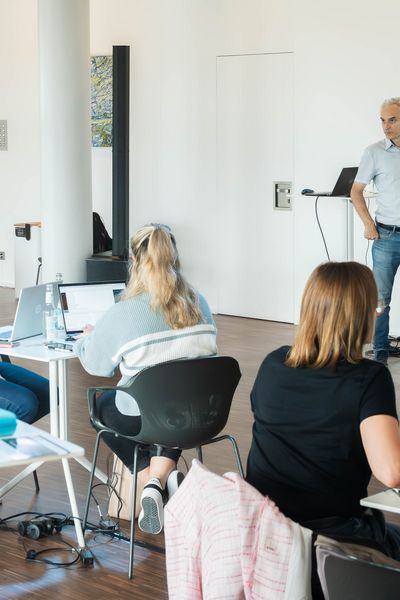 Workshop Teilnehmer hören aufmerksam den vorne stehenden Präsentierenden zu