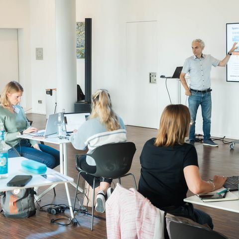 Workshop Teilnehmer hören aufmerksam den vorne stehenden Präsentierenden zu