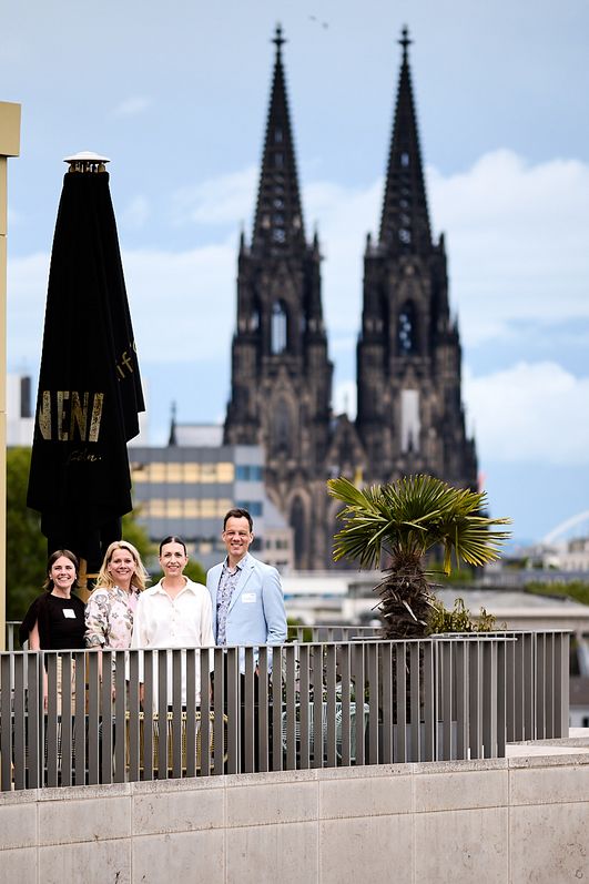 Das CCB Team draußen auf der Terrasse der Monkey Bar mit dem Kölner Dom im Hintergrund