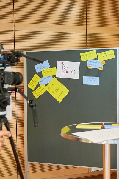 Kameramann filmt Ergebnisse eine Gruppenarbeit an Pinnwänden und Flipcharts