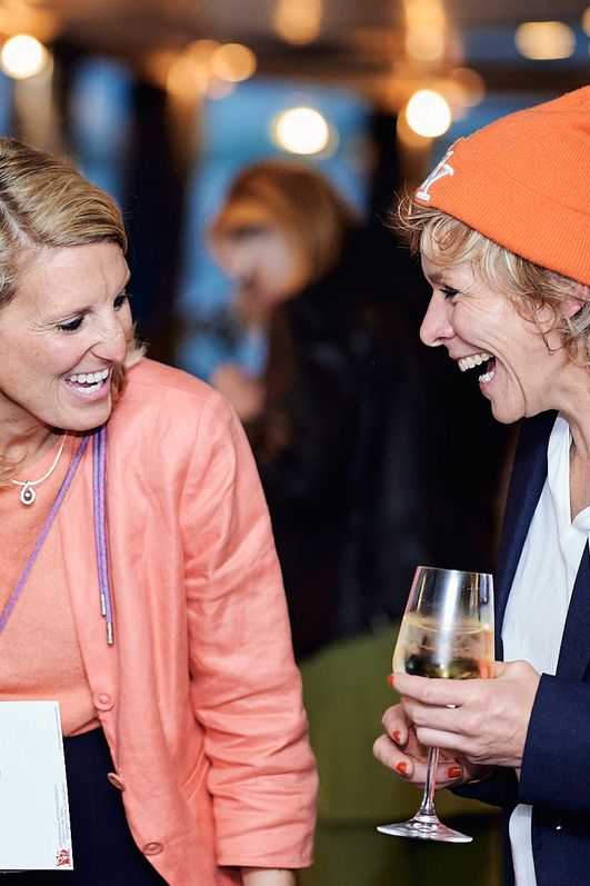 Zwei Frauen stehen nebeneinander und lachen