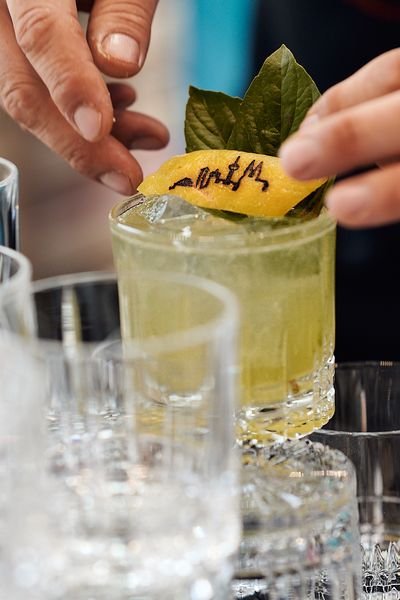 Nahaufnahme: Cocktail mit Zitronenschale auf der die Kölner Skyline eingraviert ist