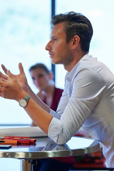 Ein Mann lehnt über einem Stehtisch und gestikuliert