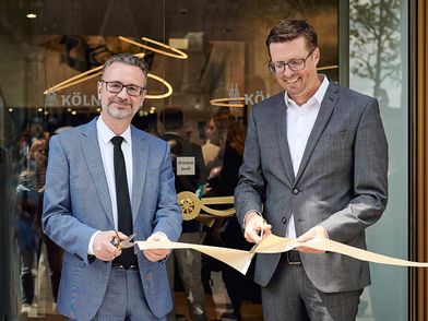 Geschäftsführer der KölnTourismus GmbH und Dezernent für Stadtentwicklung zerschneiden das Band bei der Eröfnnungsfeier der Kölner Tourist Information vor der Eingangstür