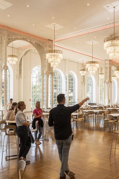 Site Inspection im Saal der Flora Köln: Ein Mann zeigt einer Gruppe Frauen den Saal