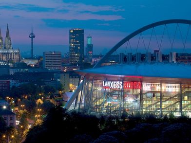 Lanxess arena mit dem Kölner Dom im Hintergrund bei Nacht