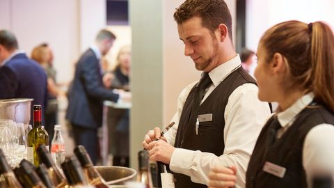 Eventpersonal öffnet Weinflaschen
