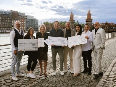 Mehrere Personen stehen in einer Reihe entlang der Spree und halten Awards in der Hand