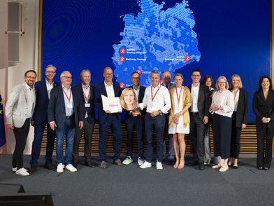 Mitarbeitende des Gateway Exzellenz Start-Up Center Köln erhält eine Förderurkunde. Mehrere Personen stehen mit der Urkunde in der Hand in einer Reihe
