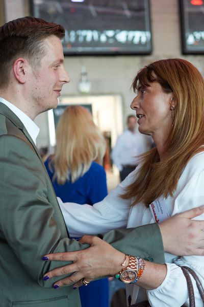 Zwei Menschen begrüßen sich auf einer Veranstaltung