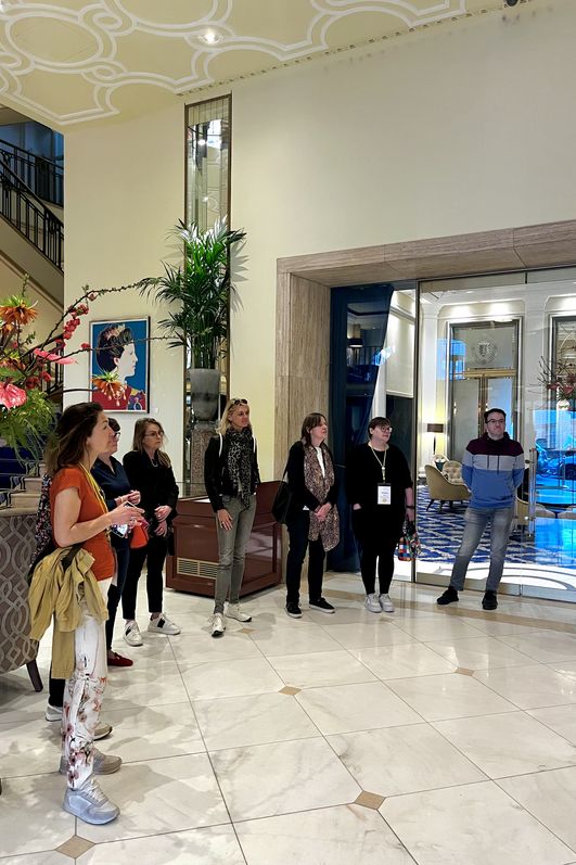 Gruppe steht im Halbkreis im Foyer des Excelsior Hotel Ernst