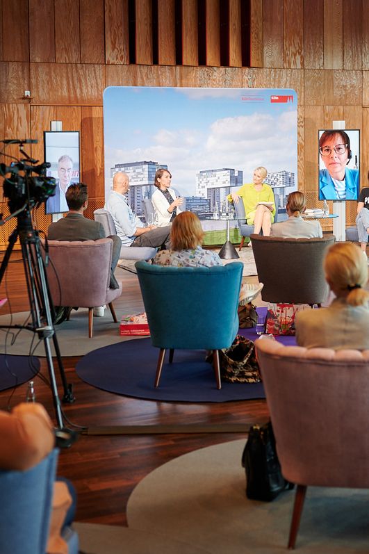 Sitzendes Publikum schaut den vorne stehenden Rednern zu