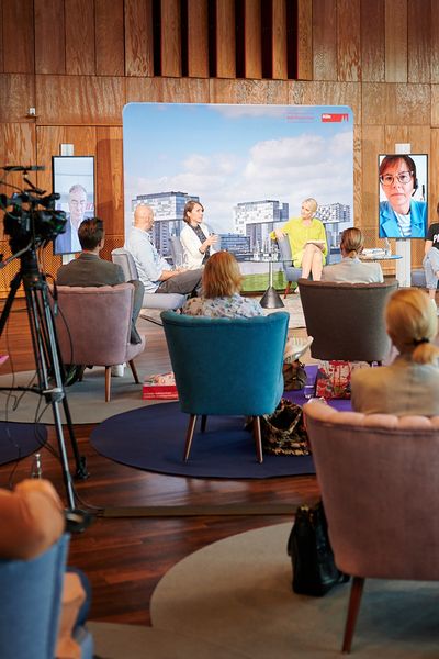 Sitzendes Publikum schaut den vorne stehenden Rednern zu