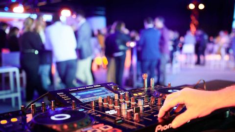 Eventtechnik. DJ Pult und im Hintergrund stehen Menschen.