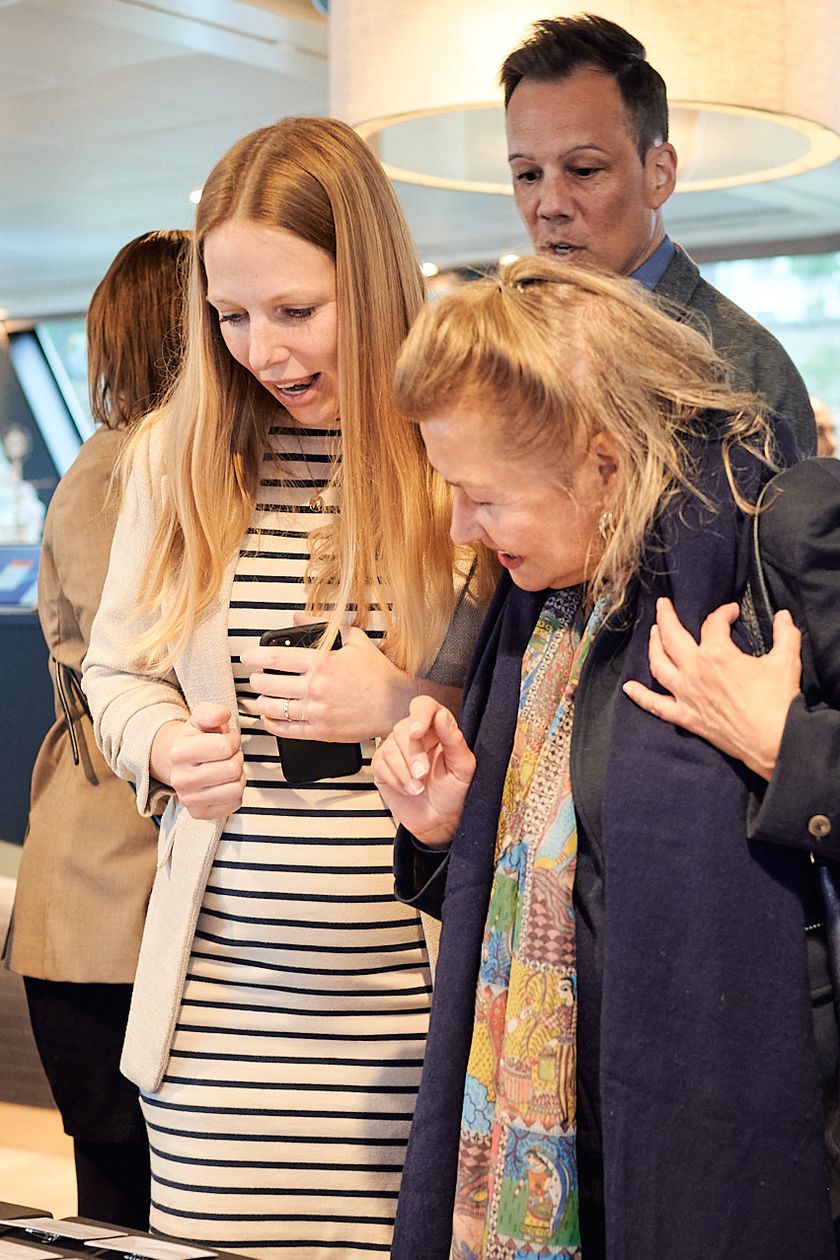 Lisa und Shirin suchen Namensschilder , im Hintergrund stehen mehrere Personen