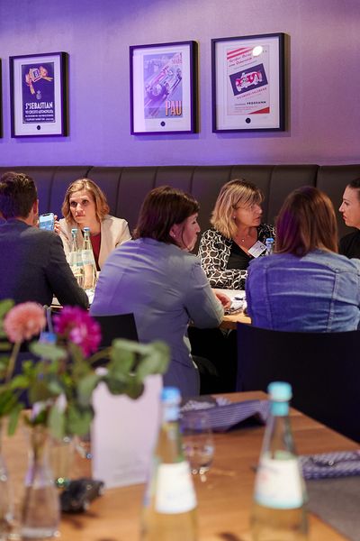 Veranstaltungsgäste sitzen um den Tisch und unterhalten sich