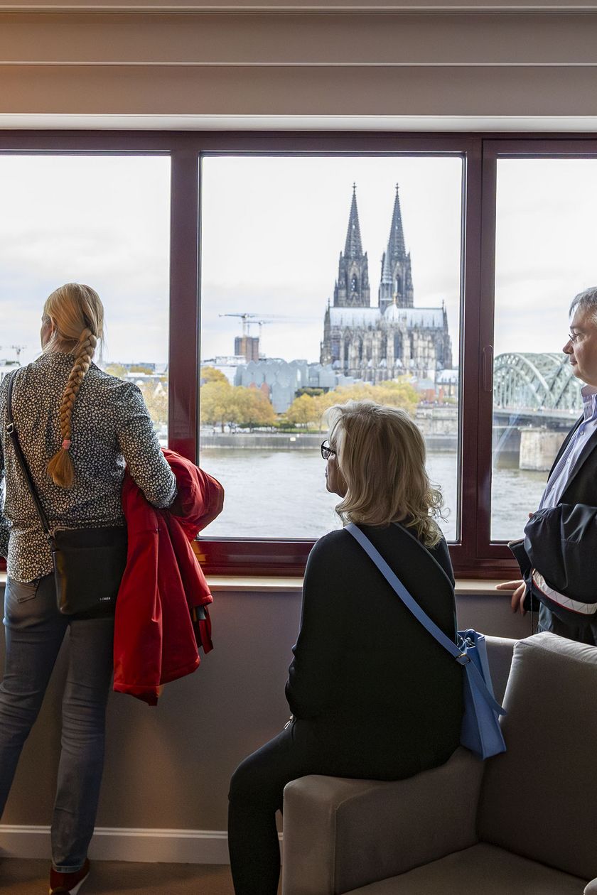 Personengruppe steht am Fenster des Hyatt Regency Köln und schaut auf den Dom