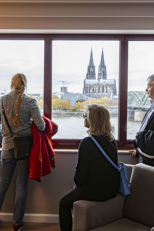 Personengruppe steht am Fenster des Hyatt Regency Köln und schaut auf den Dom