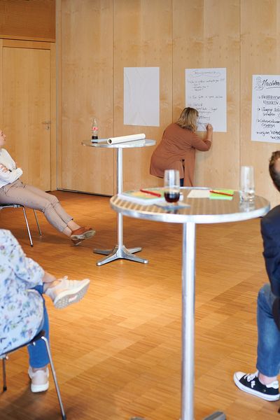 Gruppenarbeit: Eine Frau schreibt etwas auf ein an der Wand hängendes Plakat