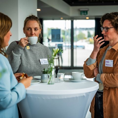 Kaffeepause im Foyer, 3 Personen trinken Kaffee am Stehtisch