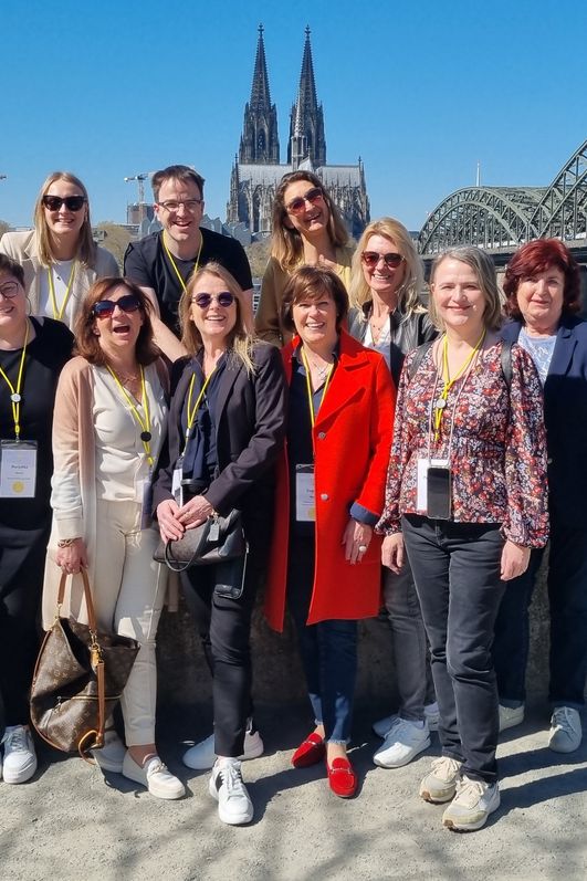 Gruppenfoto am Rheinufer mit dem Rhein und der Hohenzollernbrücke im Hintergrund
